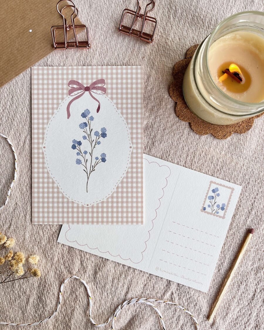 Cottagecore hangulatú őszi képeslap. A kézzel illusztrált print háttere barna gingham mintás, rajta fehér keretben és lila masnival és finomka rezgő. A képeslap hátoldalán külön kialakított hely van a címzésnek és a bélyegnek. A fotón szerepel még gyertya és boríték is. Kuckózós hangulat levelezéshez.