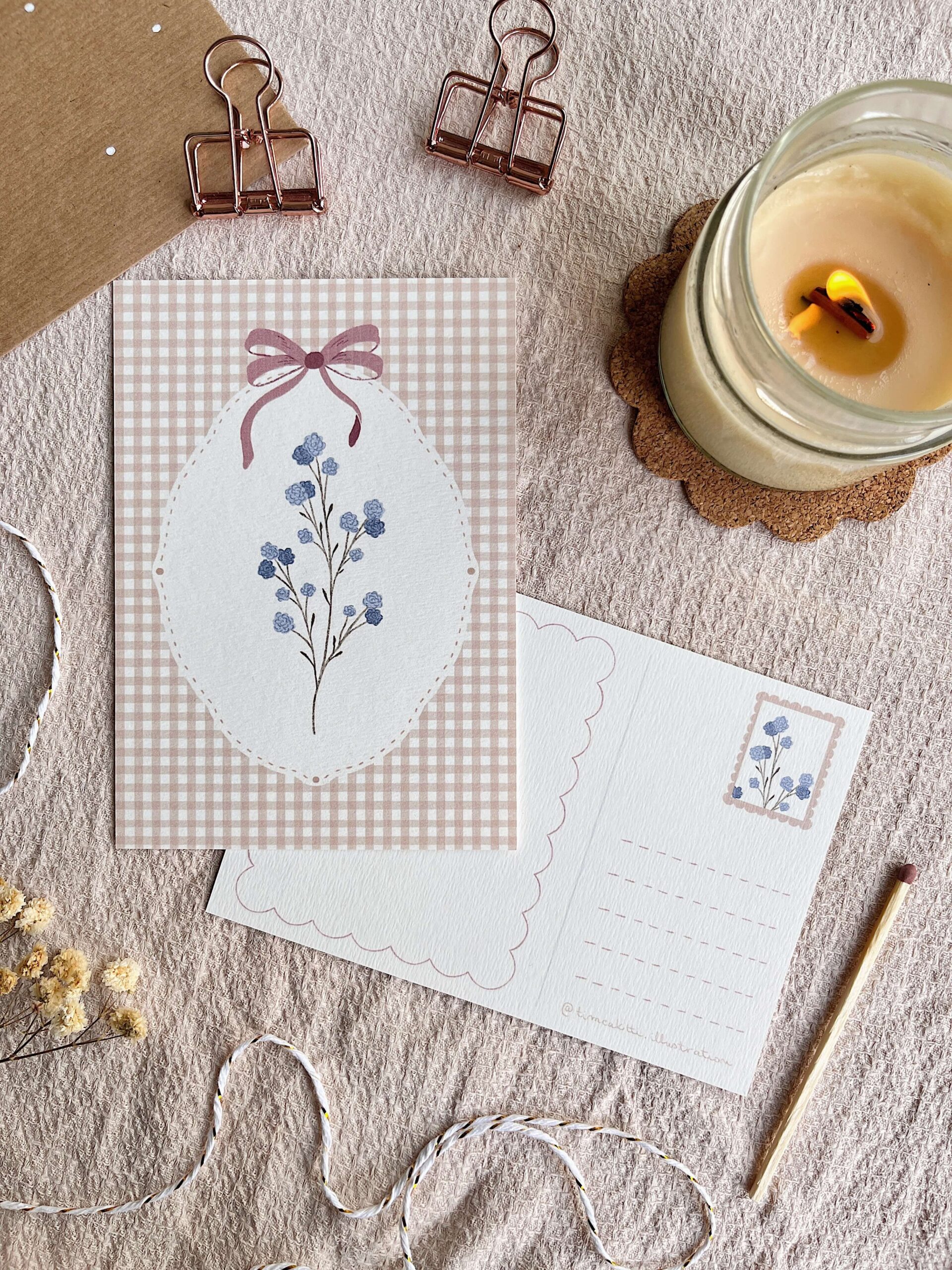 Cottagecore hangulatú őszi képeslap. A kézzel illusztrált print háttere barna gingham mintás, rajta fehér keretben és lila masnival és finomka rezgő. A képeslap hátoldalán külön kialakított hely van a címzésnek és a bélyegnek. A fotón szerepel még gyertya és boríték is. Kuckózós hangulat levelezéshez.